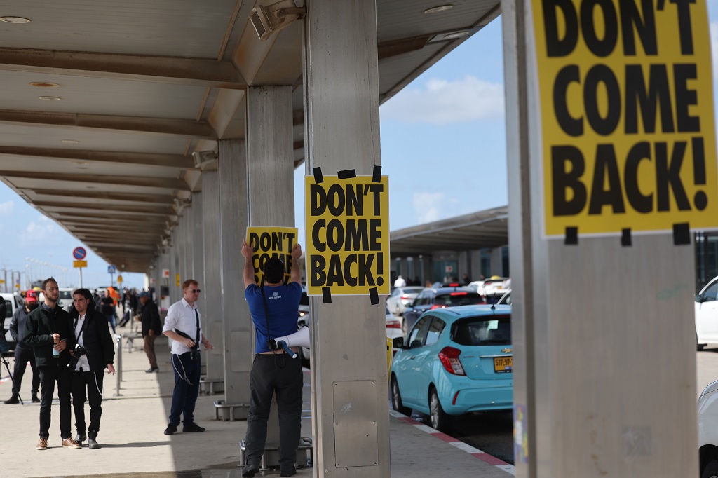 متظاهرون يعلقون ملصقات تحمل عبارة "لا تعود" قبيل سفر نتنياهو إلى برلين-تصوير: أ ف ب