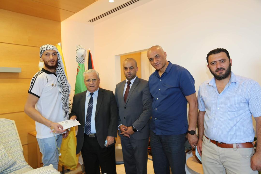رئيس جامعة القدس المفتوحة يونس عمرو خلال تسليمه الأسير المحرر الغضنفر أبو عطوان منحة دراسية 