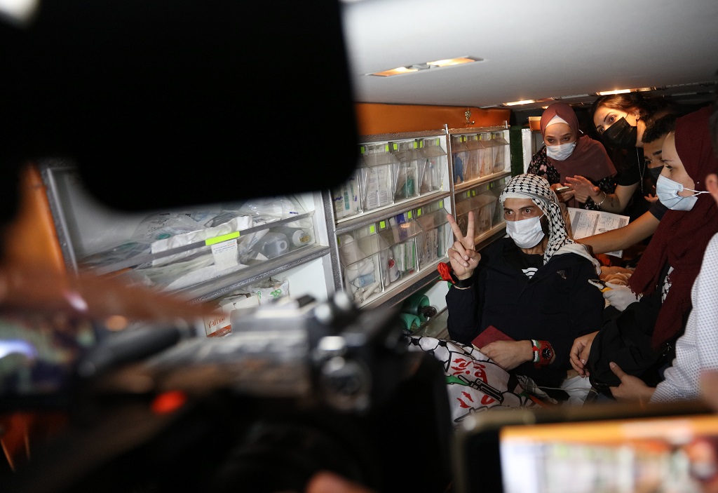 الأسير المحرر الغضنفر أبو عطوان يلوّح بشارة النصر فور وصوله إلى المستشفى الاستشاري في رام الله. (تصوير: حمزة شلش/وفا)