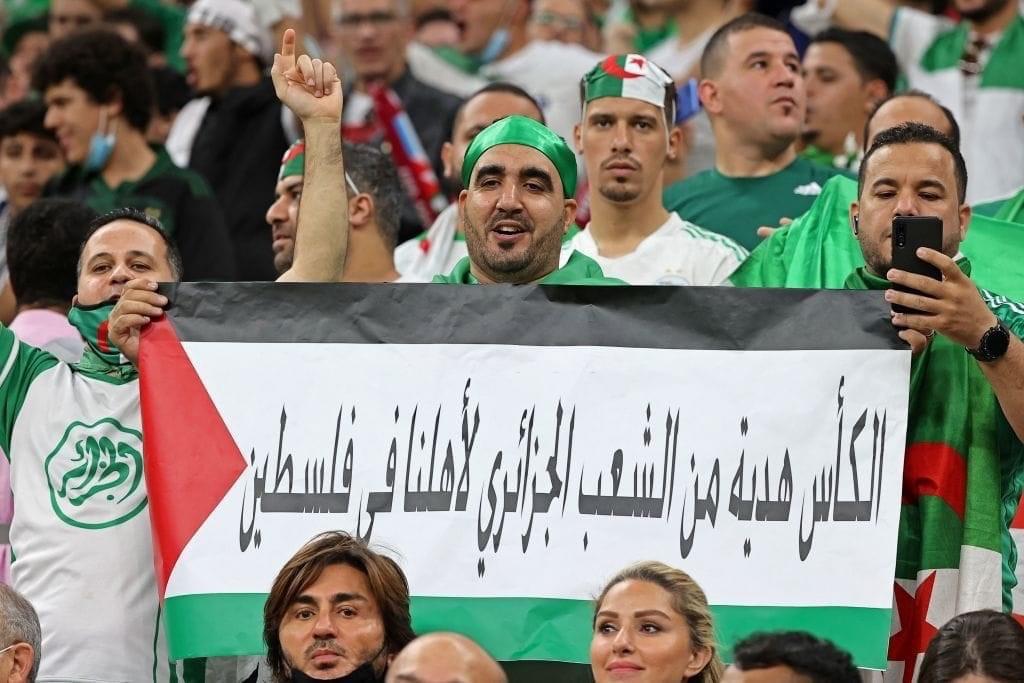 مشجعو منتخب الجزائر يرفعون علم فلسطين (الصورة لوكالة AFP)