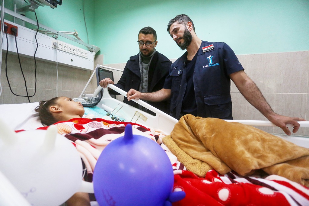 الجراح العراقي محمد الطاهر يطمأن على الطفلة مريم صباح بعد إجراء الجراحة في مستشفى شهداء الأقصى في دير البلح وسط قطاع غزة (الأناضول)
