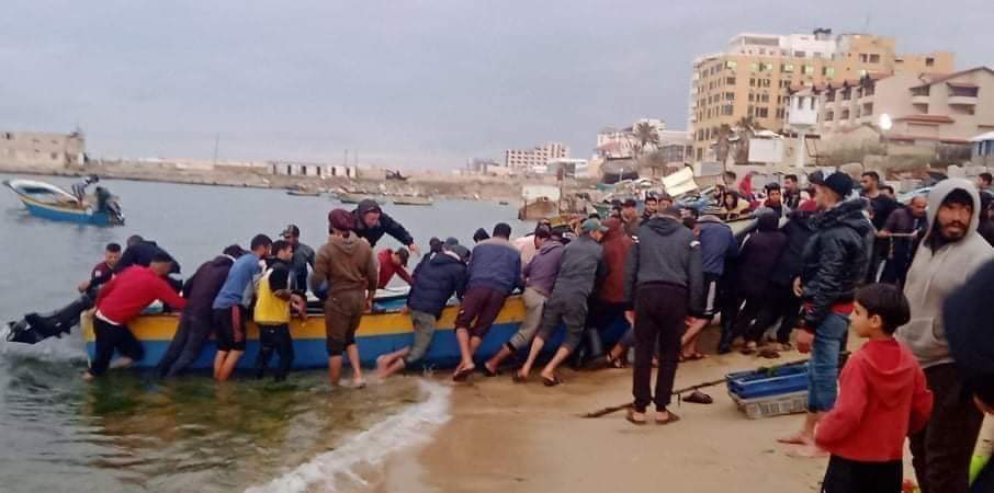 مواطنون يجرّون القارب الذي انقلب قبالة ميناء غزة إلى الشاطئ