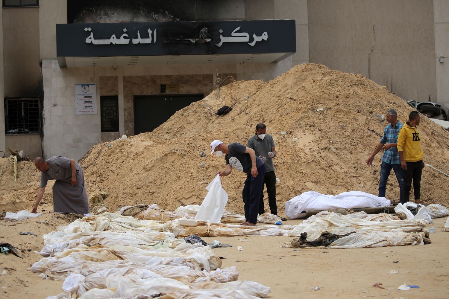 مواطنون يحاولون التعرف على جثامين اقربائهم بعد اكتشافها في مقبرة جماعية عثر عليها قرب مجمع ناصر الطبي قطاع غزة (تصوير: ا ف ب)